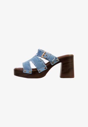 Sandal med chunky træsål, lyseblå flossede stofremme og en guldbeslået spænde på siden, åben tå og platformsål.