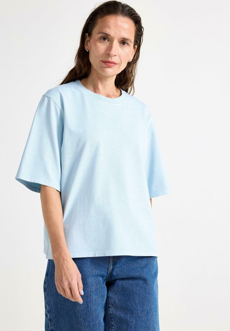 Lyseblå bomulds T-shirt med korte ærmer, løs pasform, rund hals og let tekstur, parret med højtaljede denim jeans.