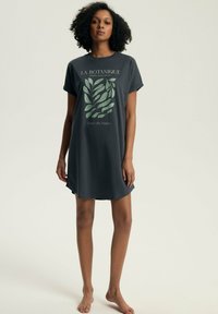 Koszula nocna z krótkim rękawem, luźny krój, w ciemnoszarym kolorze z bawełny, z zielonym rysunkiem liścia i napisem "LA BOTANIQUE" w prostym foncie.