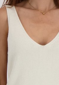 Lichtcrème geknipte tanktop met een diepe V-halslijn en geribbeld textuur. Eenvoudig ontwerp, geen patronen of zichtbare hardware details.