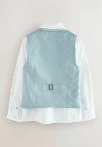 Svetlo modra satenasta jopica z gladko teksturo in osrednjim zaponko, prikazana čez belo srajco z dolgimi rokavi in gumbi na manšetah.