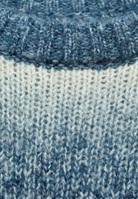 Neulepaita, jossa on ribattu sininen kaulus ja vaaleansinisestä tummansiniseksi vaihteleva lanka. Pehmeä rakenne, jossa näkyvät ompeleiden kuviot.