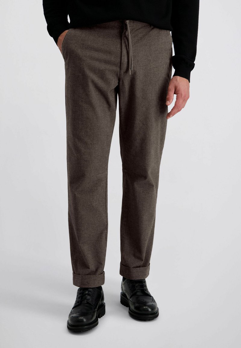 Pantalons texturés gris avec une taille à cordon, jambes droites et ourlets à revers, portés avec des chaussures à lacets noires.