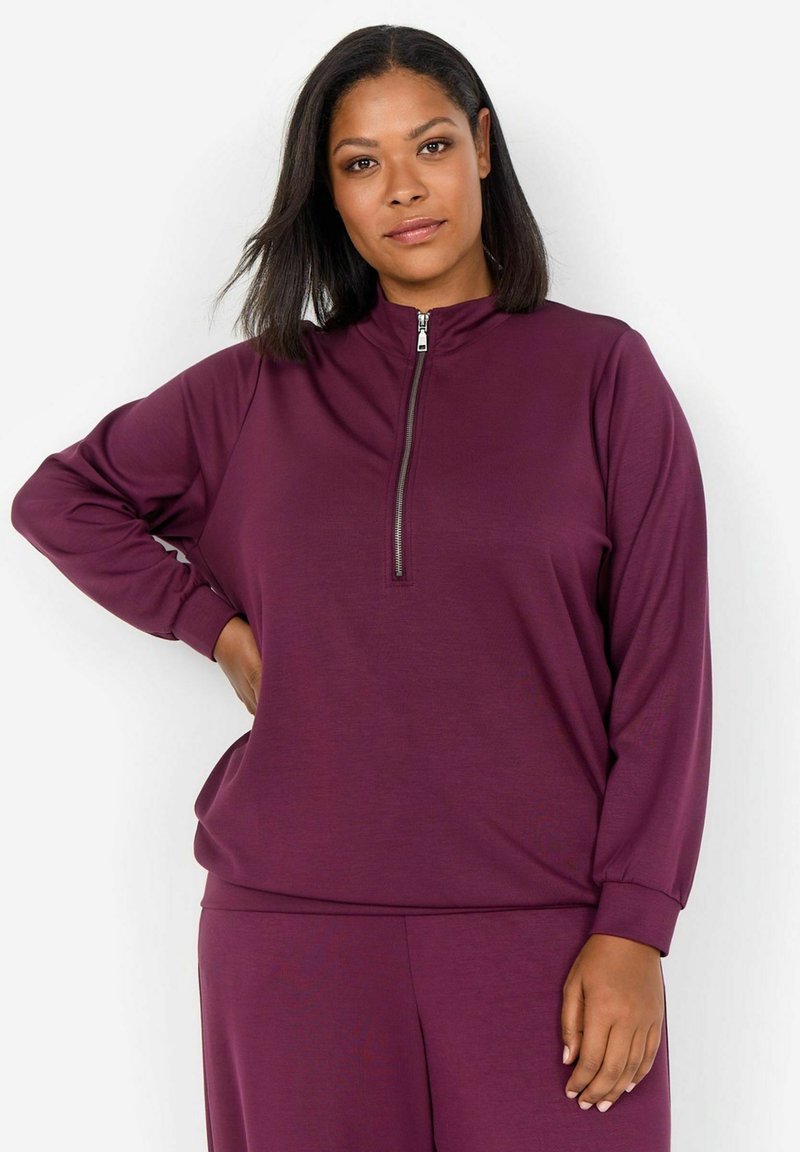 Suéter morado con media cremallera, de manga larga y corte relajado. Fabricado con un tejido suave y de textura lisa.
