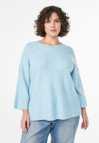 Maglione a coste di un blu chiaro, con maniche larghe a tre quarti e scollatura rotonda. Tessuto morbido, vestibilità rilassata e arriva all'altezza dell'anca.