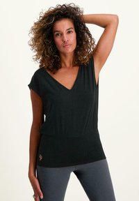 Svart kortärmad topp med V-ringning, slät textur, sammangagen midjedetalj och en diskret logotyp nära fållen.