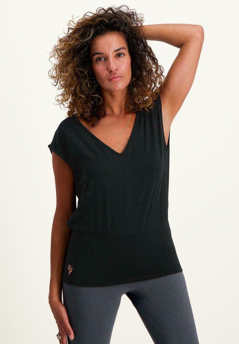 Svart kortärmad topp med V-ringning, slät textur, sammangagen midjedetalj och en diskret logotyp nära fållen.