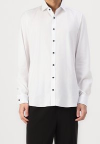 Weißes Langarmhemd aus leichtem Stoff, mit klassischem Kragen, schwarzen Knöpfen und geknöpften Manschetten. Taillierte Passform.