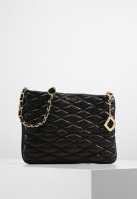 Borsa a tracolla nera trapuntata con catena dorata e un accento decorativo a forma di portachiavi. Presenta un motivo a diamante e un dettaglio del logo sul davanti.