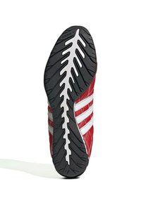 Röd sportsk shoe med strukturerad svart gummisula, vita ränder på sidan och en slät, läderliknande yta.