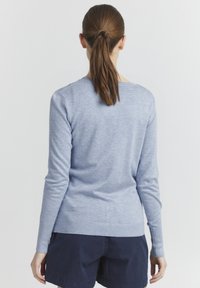 Pull bleu clair à manches longues avec un encolure ronde et un ourlet côtelé. Texture douce, silhouette ajustée et design épuré et minimaliste.