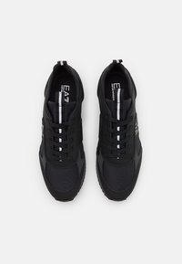 Svarta atletiska skor med övre del i mesh och syntetmaterial, utrustade med texturerad sula, snörning och vita accentstreck.