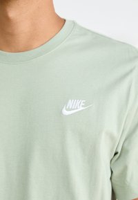 Világoszöld pamut póló kerek nyakkivágással és rövid ujjakkal. Bal mellen fehér hímzett Nike logó található.