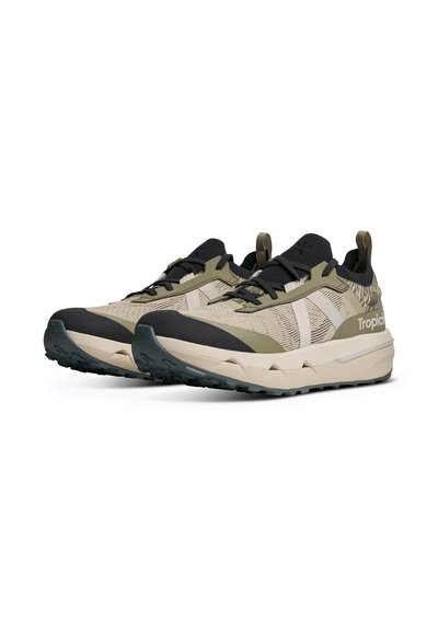 Paire de chaussures de sport beige et vert olive avec accents noirs, semelles épaisses, design à lacets et marquage "Tropic" sur le côté.