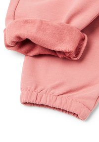 Hladký růžový textilní rukáv s elastickým manžetovým zakončením, ukazující jak hladký vnější povrch, tak texturovaný vnitřek materiálu.