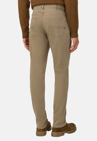 Beżowe bawełniane spodnie o prostym kroju, z tylnymi kieszeniami i prostą talią, zestawione z brązowymi zamszowymi butami.