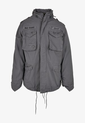 Sako vojenského stylu šedé barvy s vysokým límcem, několika předními kapsami, nastavitelným šňůrkovým lemem a vyšitými textovými detaily.