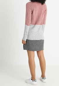 Abito in maglia con un design a blocchi di colore rosa, grigio e grigio scuro. Presenta una texture a coste, maniche lunghe e una silhouette aderente.