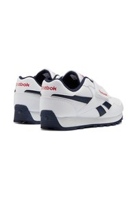 Zapatillas de cuero blancas con acentos en azul marino, que cuentan con un talón texturizado, cuello acolchado y el logo "Reebok" en el lateral y en la parte trasera.