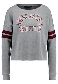 Szary sweter z dzianiny o prążkowanej teksturze, szerokim dekolcie i bordowych paskach na rękawach. Zawiera napis "ABERCROMBIE AND FITCH" w wyrazistym kroju.