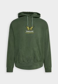 Zelená mikina s kapucí, přední kapsou, šňůrkou a vyšitým designem motýla. Na ní je nápis "PAPILLONS Botanická výstava."