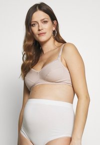 Sutiã de amamentação bege com alças ajustáveis e acabamento em renda, combinado com cuecas brancas de cintura alta em tecido suave.