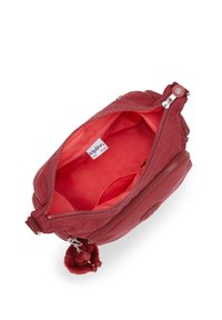 Rød lædertaske med dobbelt lynlås, der har et blødt stofinteriør. Inkluderer en pelsagtig pom-pom accent. Kompakt, rund form.