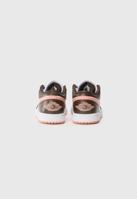 Sneaker in pelle marrone con accenti rosa, midsole bianca e dettagli del logo sul tallone. Superficie texturizzata e colletto imbottito.