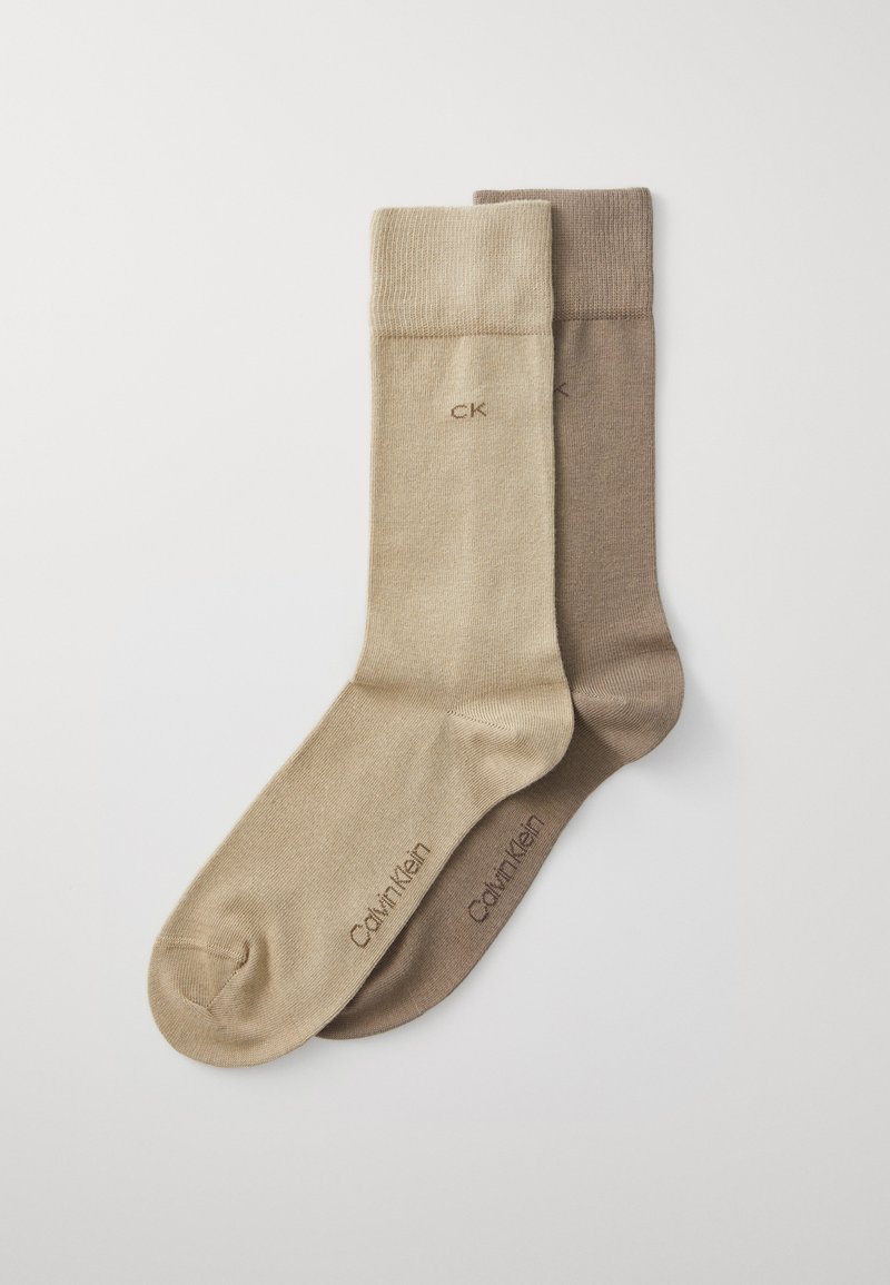 Calze beige e marroni realizzate in un tessuto morbido, con un polsino a coste e il logo "Calvin Klein" stampato di lato.