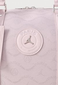 Rózsaszín szövet táska, amelyen a „Paris Saint Germain” logó kör alakú folton található, a texturált mintázat pedig az Eiffel-toronyt és a márkanevet ábrázolja.