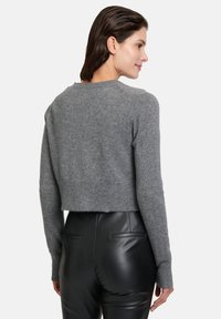 Pull court gris foncé en tricot doux avec un col rond et une finition côtelée, associé à un pantalon noir ajusté avec des poches arrière.
