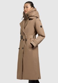 Trench coat beige con vita regolabile, grande cappuccio, bottoni doppi e tasche laterali. Texture liscia e vestibilità su misura.