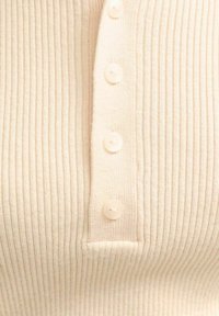 Maglione a coste color crema con design abbottonato e cinque bottoni coordinati lungo il davanti, tessuto morbido e forma aderente.