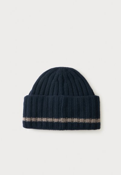 Bonnet d'hiver en tricot côtelé bleu marine foncé avec bord replié et une seule bande gris clair près du bord, posé à plat sur un fond clair.