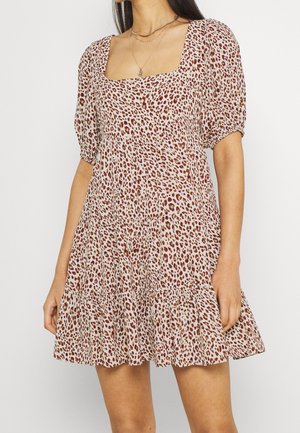 Vestido de manga corta en una tela beige con manchas de leopardo marrón, con escote cuadrado y dobladillo acampanado. Diseño ligero y fluido.