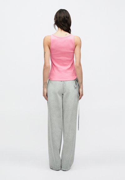 Ροζ ριμπ μπλουζάκι με στρογγυλή λαιμόκοψη, συνδυασμένο με φαρδιά γκρι τζιν παντελόνια που διαθέτουν κορδόνι στη μέση.