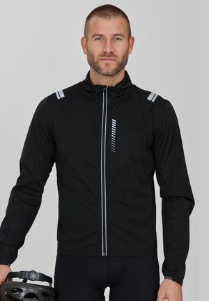 Schwarze Radjacke mit Reißverschluss vorne, ausgestattet mit reflektierenden Streifen auf den Schultern und einem vertikalen Muster auf der Brust. Leichtes Material.