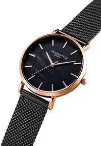 Reloj analógico negro con una esfera redonda, acentos en oro rosado y una correa de malla negra; presenta marcadores minimalistas y una esfera brillante.