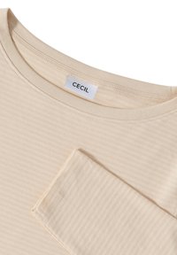 Beige striped T-shirt with a round neckline and long sleeves. Features a pocket detail on the left side. Made of soft, lightweight fabric.