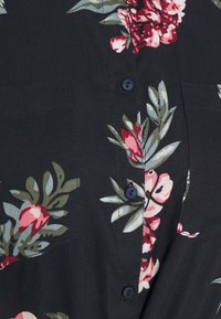 Blusa floreale in blu scuro con stampa botanica rosa e verde, dotata di due tasche frontali e bottoni blu lungo la pattina.