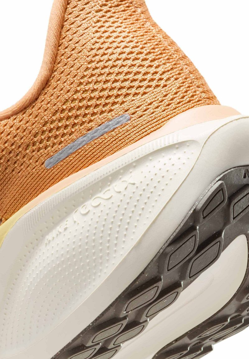 Zapatilla de correr ligera con parte superior de malla naranja, acentos plateados, plantilla blanca acolchada y suela exterior de goma negra texturizada.