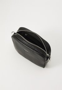 Borsa in pelle nera con chiusura a doppia zip, forma rotonda, texture liscia, dettagli in metallo argentato e un compartimento interno visibile.