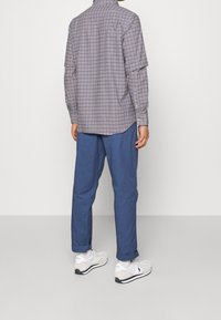 Rutiga skjortor i blått och vitt, med långa ärmar och krage. Matchas med ljusblå byxor och vita sneakers.