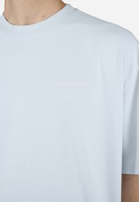 Ljusblå bomulls-T-shirt med rund halsringning och korta ärmar. Broderad "PEGADOR"-logotyp i vitt på bröstet. Mjuk textur.