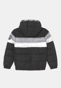 Gewatteerd jack met zwart materiaal en horizontale strepen in zilver en wit, een capuchon en elastische manchetten. Logo-embleem op de linker schouder.