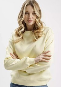 Jasnożółta, długorękawowa bluza z okrągłym dekoltem i prążkowanymi mankietami. Miękka tekstura oraz luźny krój, idealna na codzienne noszenie.