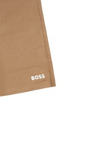 Beige shorts van gladde stof met een aansluitend ontwerp. Bevat een witte "BOSS" logo vlakbij de zoom. Strakke snit en minimale stikdetails.