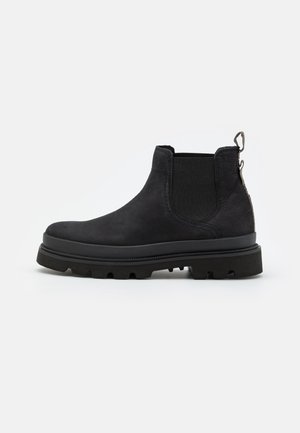 Bottine Chelsea en cuir noir avec semelle épaisse, panneau latéral élastique et languette à l'arrière, montrée de profil sur un fond uni.