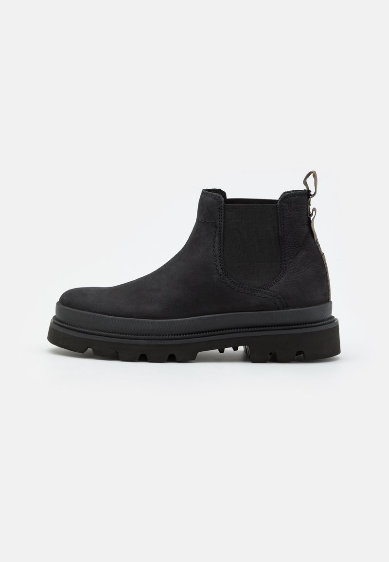 Bottine Chelsea en cuir noir avec semelle épaisse, panneau latéral élastique et languette à l'arrière, montrée de profil sur un fond uni.