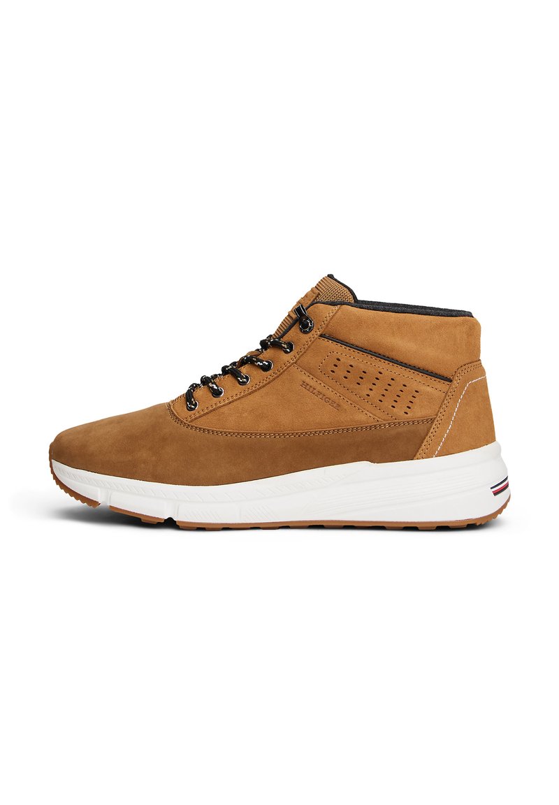 Baskets montantes en suede marron avec lacets noirs, détail perforé sur les côtés, et semelle en caoutchouc blanc avec un accent rayé au niveau du talon.